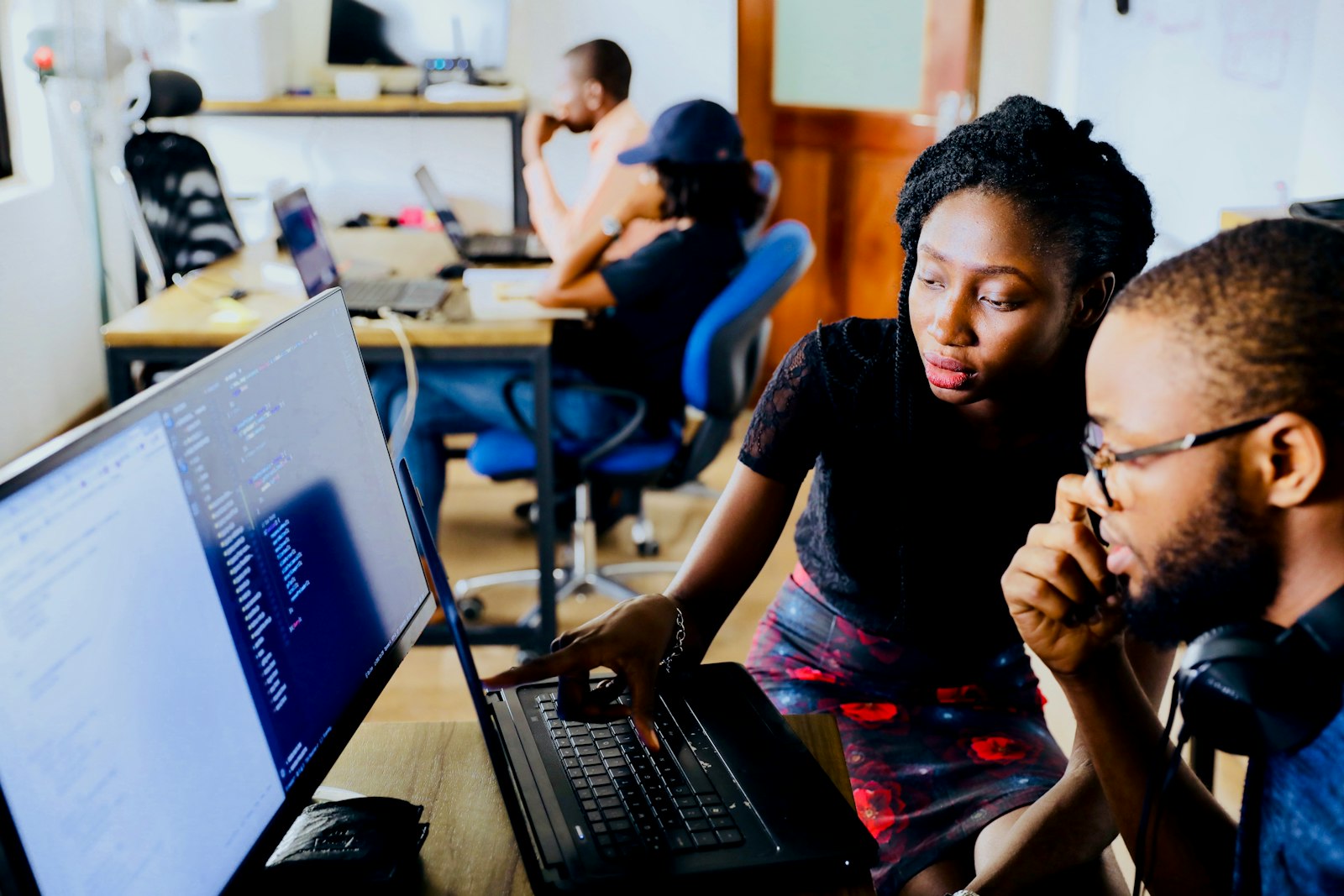 Two engineers reviewing code together on a large monitor